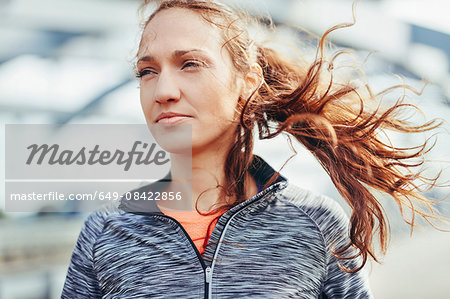 Portrait of female runner with flyaway hair on city footbridge