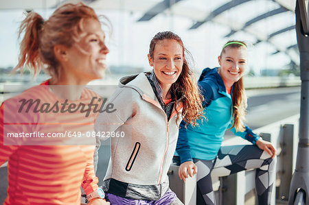 Portrait of three female runners on city footbridge