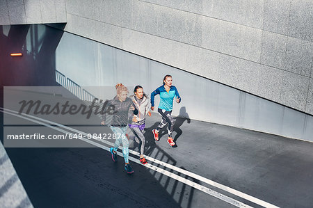 Three female runners racing up city underpass