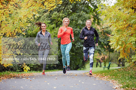 Three female runners running along park path