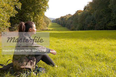 Young woman sitting in field looking at landscape, Great Missenden, Buckinghamshire, U.K