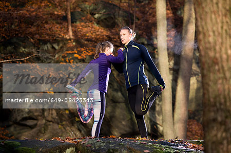 Couple in forest leaning against each other leg raised holding foot stretching