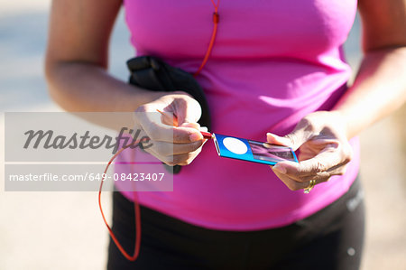 Cropped mid section of mature woman plugging audio jack into mp3 player