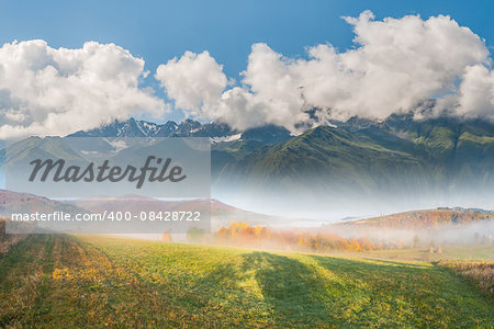 Beautiful landscape with meadow, mountain, fog and clouds