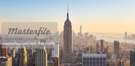 New York City. Manhattan downtown skyline with illuminated Empire State Building and skyscrapers at sunset seen from Top of the Rock observation deck. Vertical composition.