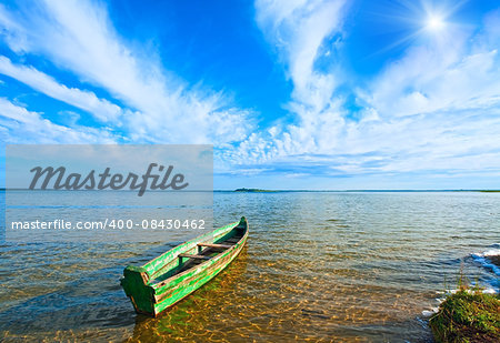 Old wooden fishing boat on summer lake bank and sunshine in blue sky (Svityaz, Ukraine)