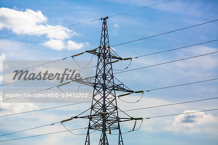 Electricity pylon silhouetted against blue sky background. High voltage tower.