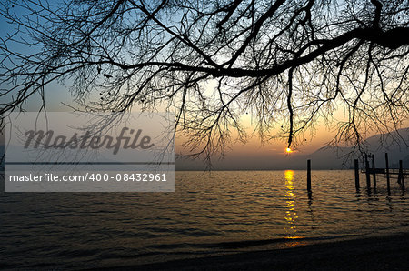 sunset over the lake major with the mists of the horizon and mountains in the background on a winter afternoon, Maccagno - Lombardy, Italy