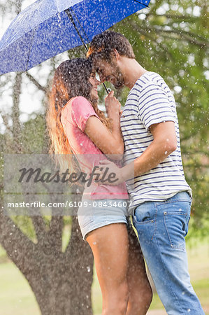 Cute couple hugging under the umbrella in the park