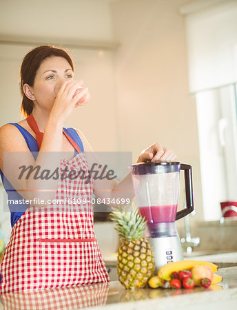 Woman drinking smoothie in kitchen