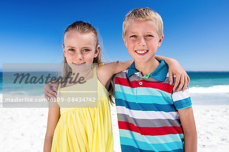 Cute siblings with arms around on the beach