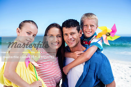 Cute family holding wind toys on the beach