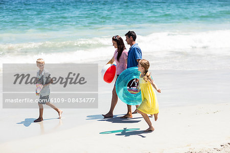 Cute family holding beach equipment on the beach