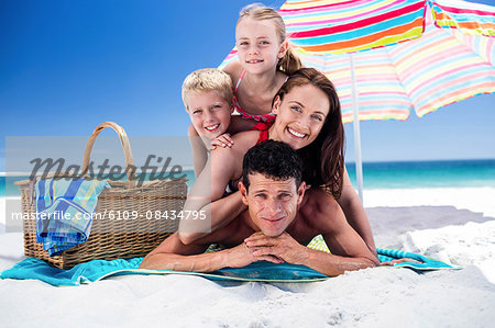 Cute family lying on towels on the beach