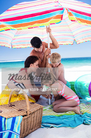 Cute family setting their umbrella on the beach