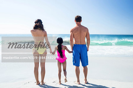Cute family holding hands on the beach