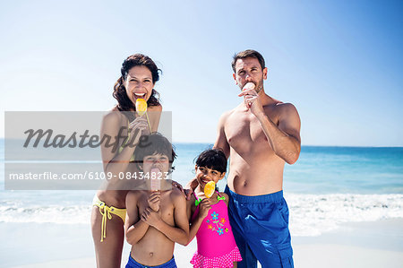 Cute family eating ice creams on the beach