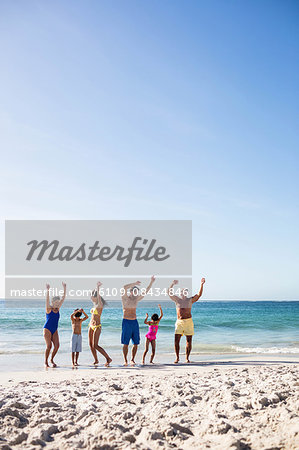 Cute family with arms outstretched on the beach