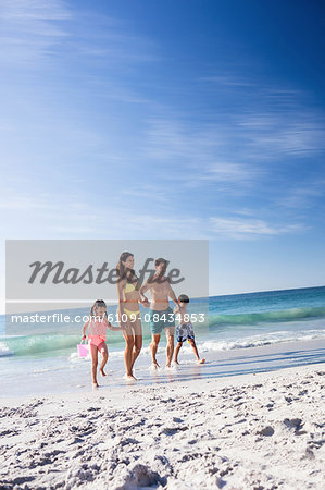 Cute family running together on the beach