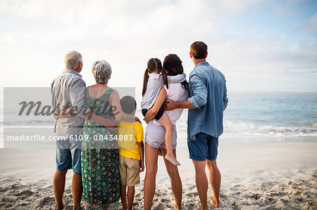 Cute family facing the sea on the beach