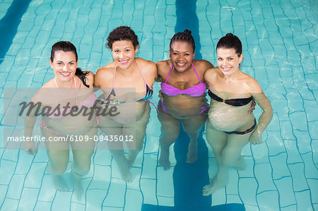 Smiling regnant woman posing together at the swimming pool