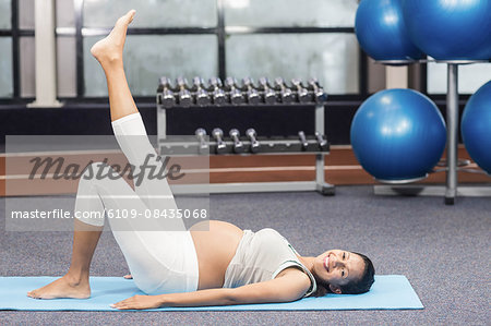 Pregnant woman doing exercise on mat at the leisure center
