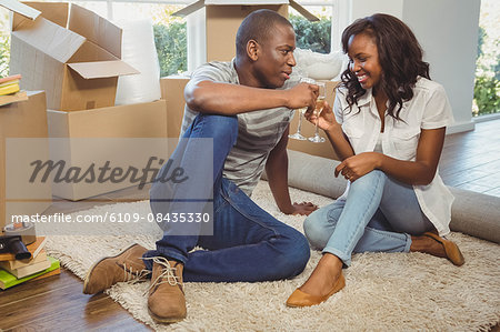Ethnic couple toasting with champagne in their new house