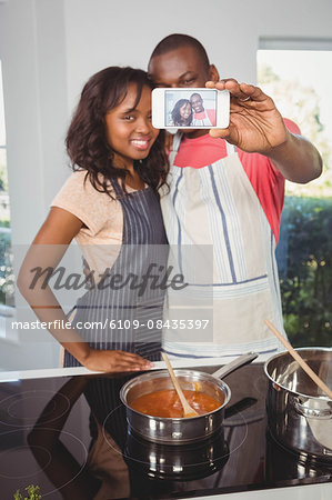 Ethnic couple taking selfie in the kitchen