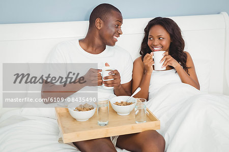 Ethnic couple having breakfast in bed in the bedroom