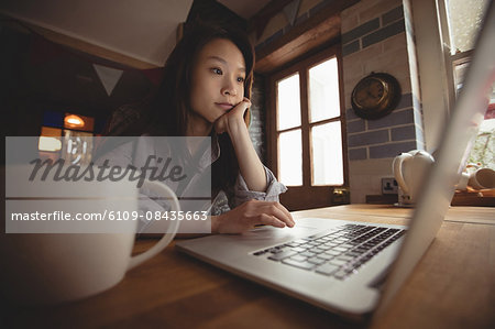 Brunette using laptop in the kitchen at home