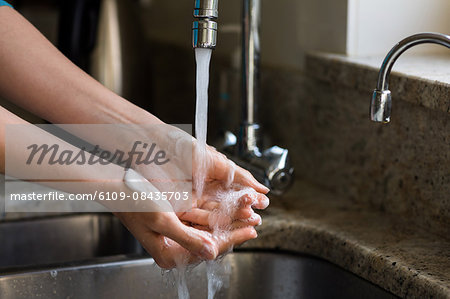 Pretty woman washing her hands in the kitchen