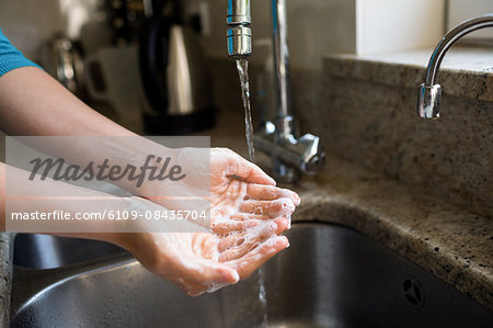 Pretty woman washing her hands in the kitchen