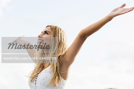 Beautiful blonde woman with arms outstretched in the coastline