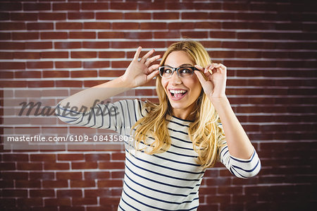 Blonde woman posing with glasses on brick wall