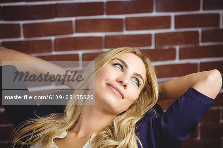 Blonde woman relaxing in chair on brick wall