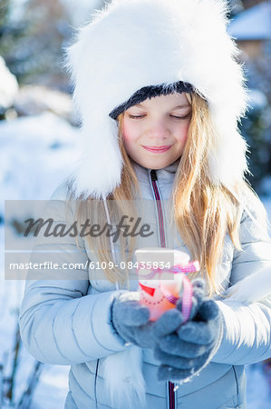 Cute girl holding a cup of tea on a beautiful snowy day