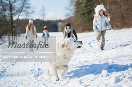 Family playing with dog on a beautiful snowy day
