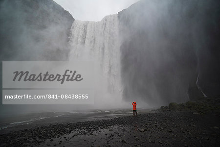 Tourist taking a photo in the spray at Skogafoss Waterfall, Skogar, South Region (Sudurland), Iceland, Polar Regions