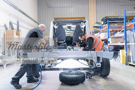 Workers fitting chassis on motorhome production line