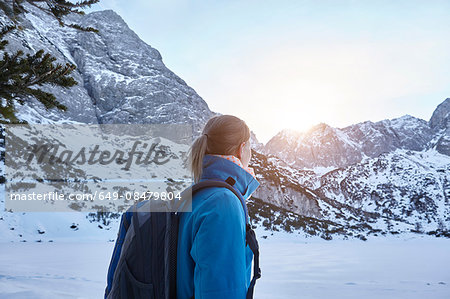 Young woman hiking in snow and watching the sun on mountain top, Austria