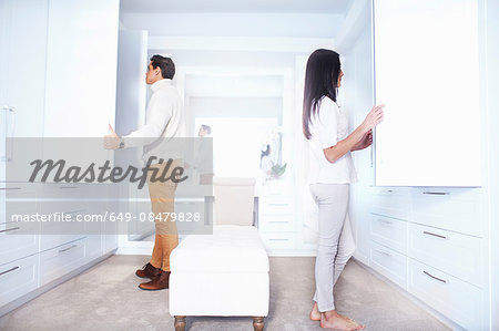 Young couple looking in bedroom closets