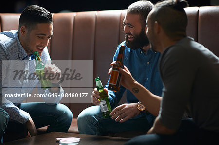 Three male friends chatting and drinking in traditional UK pub