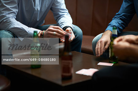 Hands of three men playing cards in traditional UK pub