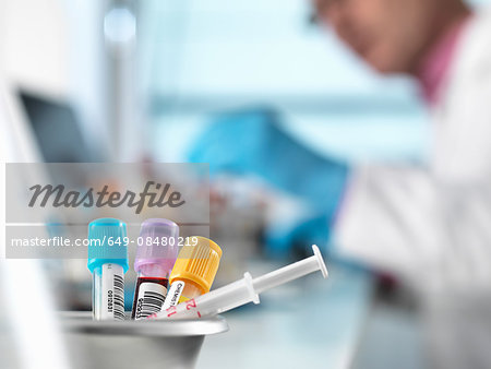 Blood samples for medical testing on desk, doctor in background