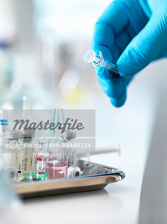 Doctor placing syringe back onto tray with drug vials Doctor placing syringe back onto tray with drug vials