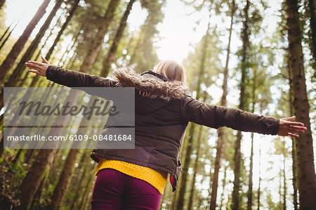 Beautiful blonde woman with arms outstretched in the woods