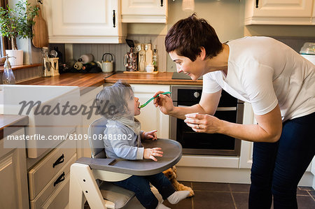 Cute mother feeding her baby in the kitchen