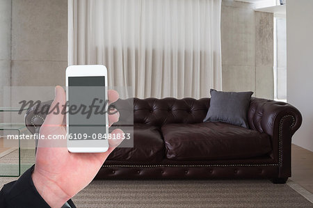 Man holding smartphone in living room at home