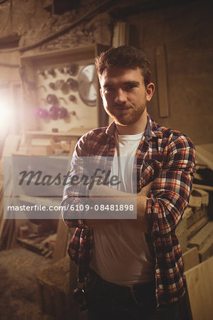 Carpenter smiling at the camera in a dusty workshop