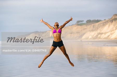 Woman in bikini jumping on beach